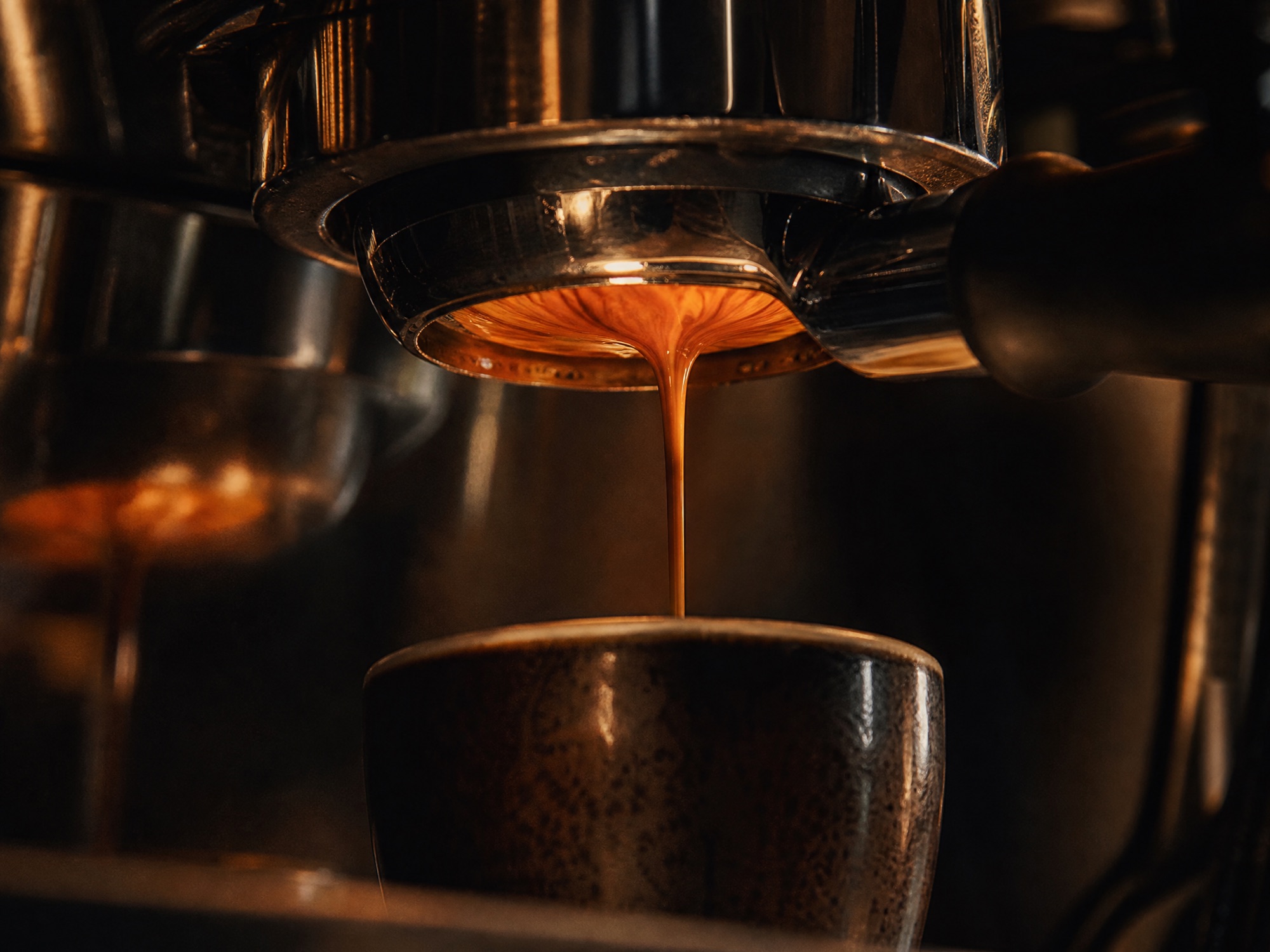 Rich espresso crema flowing from a portafilter into a small cup